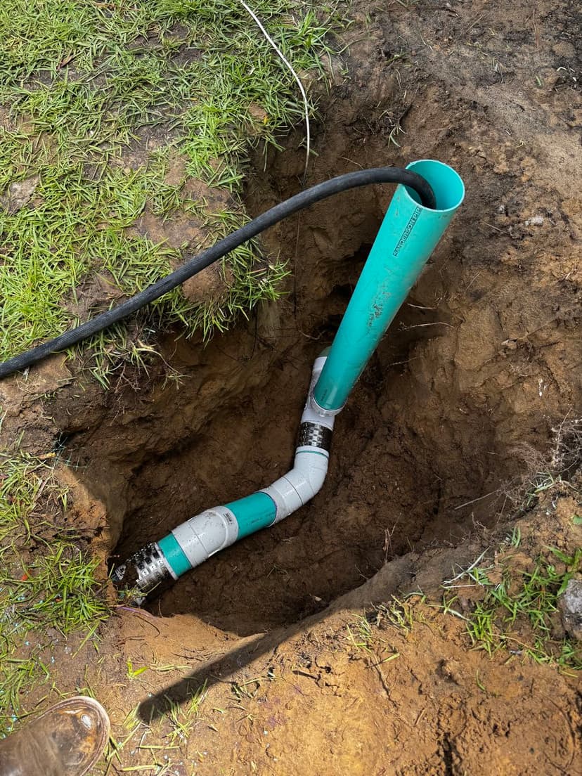 PVC pipe installation in a dug trench with grass surrounding the area.